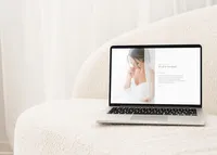 Laptop on a white sofa showing a light and airy showit template for photographers