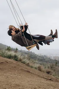Artsy and joyful couple photoshoot on a swing in Barcelona, emphasizing movement, laughter, and authentic storytelling.
