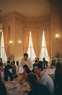 Candid film photography of a wedding lunch at Letenský zámeček, featuring guests enjoying the meal in a historic ballroom.