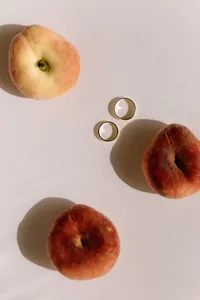 Close-up of gold wedding bands with peaches for a summer garden wedding inspiration.