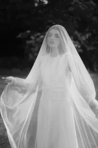 Poetic and cinematic portrait of a bride underneath a sheer veil, emphasizing soft light and emotional storytelling.
