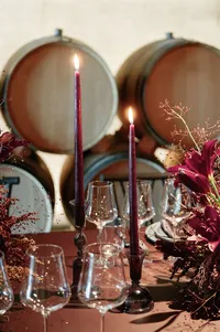 Romantic rehearsal dinner table set inside a modern winery cellar with rich florals and candlelight at Lucid Wild Estate.