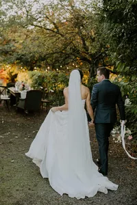 Bride and groom walking through garden setting during outdoor estate-style wedding