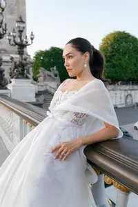 Close portrait of the bride showing the silk and lace details of her gown, pearl earrings, and ponytail hairstyle.