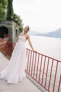 Model in textured lace gown standing by red railing at Villa Cipressi overlooking Lake Como