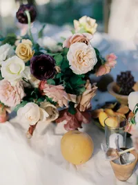 Reception centerpiece featuring Cocoa Loco roses, blush garden roses, burgundy ranunculus, and clay candle holders at a Lake Oswego Oregon winery wedding.