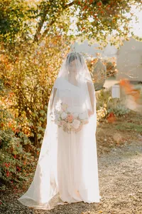 Bride holding bouquet under soft autumn light in outdoor garden wedding setting