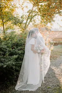Bride wearing veil holding bouquet in garden wedding setting with soft natural light