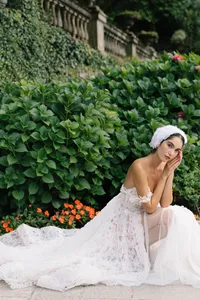 Model in lace gown seated in Villa Cipressi garden during Lake Como editorial