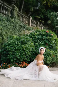 Model in lace gown seated in lush garden at Villa Cipressi in Lake Como editorial