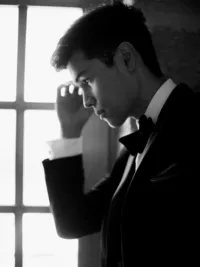 Black and white portrait of groom sitting at Sunstone Winery entrance waiting for his bride.