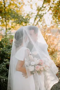 Couple portrait through veil with bouquet in outdoor garden wedding portrait
