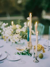 Champagne coupe beside taper candles, grapes, and pears on the reception table, an old-world detail from a Santa Barbara wedding editorial by Yuliya Supin Design