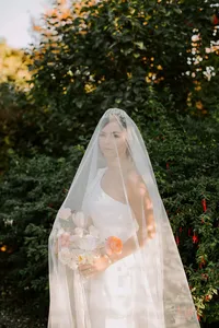 Bride portrait through veil holding bouquet in romantic outdoor wedding setting
