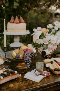 Wedding dessert table with cake, florals, and fruit styling in outdoor garden setting