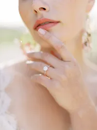 Close-up of bride and groom holding hands with wedding rings during Sunstone Winery ceremony.