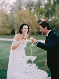 Bride and groom pouring champagne together over a coupe tower, a celebratory reception moment from a Santa Barbara wedding editorial by Yuliya Supin Design
