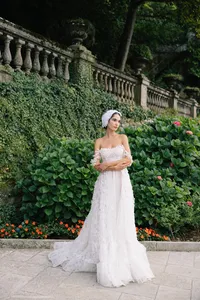 Model in lace gown stanting in garden at Villa Cipressi surrounded by greenery and florals