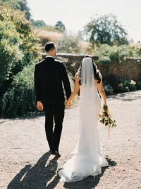 Bride and groom walking hand in hand toward their outdoor garden reception during a romantic winery wedding in Lake Oswego Oregon.