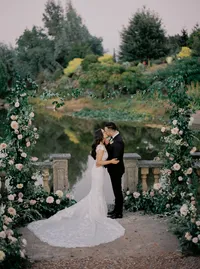 Bride and groom kissing under the floral ceremony arch at sunset during their Lake Oswego Oregon winery wedding.