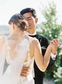 Bride and groom dancing together with flowing veil during romantic vineyard wedding.