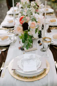 Luxury wedding place setting with menu card, fine china, and gold flatware on garden table