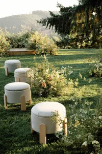 Rounded ottoman chairs arranged near organic floral installation and ceremony arch overlooking the Oregon valley.