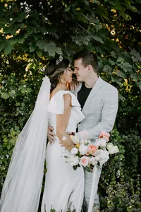 Bride and groom portrait surrounded by greenery in an outdoor estate-inspired wedding setting