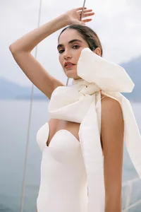 Model wearing structured white bridal piece with oversized bow photographed on Lake Como