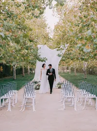 Newlyweds walking the recessional between rows of ribbon-tied bistro chairs, from a Santa Barbara wedding editorial by Yuliya Supin Design