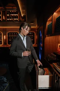 Groom seated in a candlelit speakeasy room with live music, waiting for his bride before rehearsal dinner at Lucid Wild Vineyard.