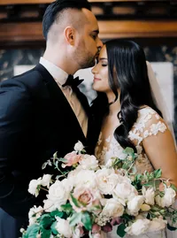 Bride and groom embracing during their first look as the groom kisses her forehead while she holds a bouquet of garden roses before their Lake Oswego Oregon winery wedding