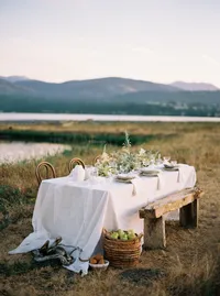 Outdoor wedding tablescape with lake and mountains in natural setting