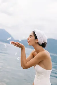 Close-up of model in soft bridal styling, blowing feathers on Lake Como fashion editorial