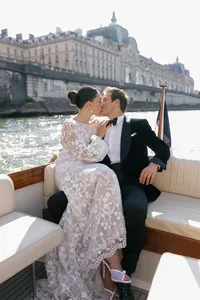 Bride and groom seated together on the boat with historic Paris architecture behind them