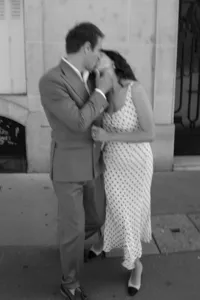 Black and white motion portrait of the couple sharing a kiss during their engagement session, the bride wearing a white polka-dot dress and the groom in a brown suit.