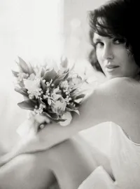 Black-and-white close-up of a small floral wrist corsage against the bride's gown, a refined detail from a Santa Barbara wedding editorial by Yuliya Supin Design