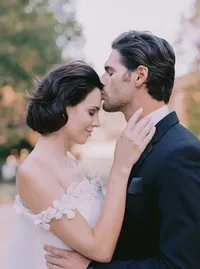 Bride's dimensional floral appliqué gown detail as she rests her hand on the groom's lapel, from a Santa Barbara wedding editorial by Yuliya Supin Design