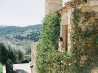 Bride standing on balcony overlooking rolling hills of Santa Ynez Valley.