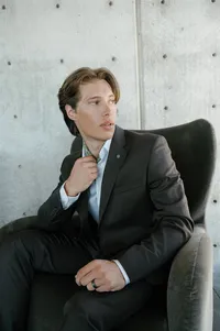 Groom seated in an intimate setting before the rehearsal dinner, waiting for his bride.