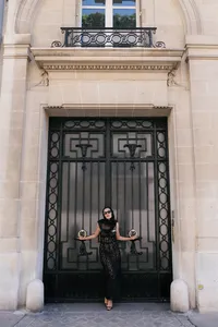 Portrait of the bride standing beside historic black iron gates in Paris during the engagement session.