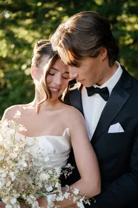 Bride leaning into groom as he holds her close, bouquet resting against her couture gown.