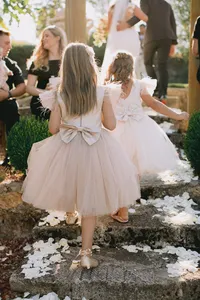 Flower girls wearing dusty pink tulle dresses with bows walking down the garden path after the ceremony at a romantic winery wedding in Lake Oswego Oregon.