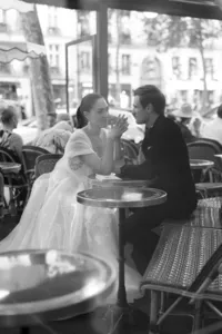 Black and white portrait of the bride and groom sharing a quiet conversation together inside Café de Flore.