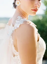 Close-up portrait of bride showing elegant hair and floral earrings during Sunstone Winery wedding.