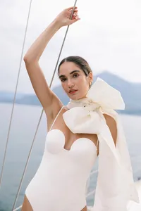 Model in structured white bridal look with oversized bow detail photographed on Lake Como for fashion editorial