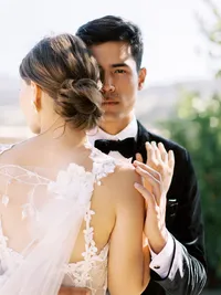 Groom looking toward camera while bride leans toward him during Sunstone Winery vineyard wedding portrait.