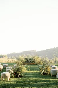 Bride and groom exchanging vows with officiant, guests seated, and floral-lined aisle at Lucid Wild Vineyard winery.