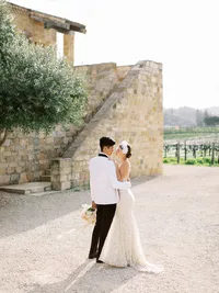 Bride wearing unique bridal headpiece with groom in white tuxedo after ceremony at Sunstone Winery wedding.