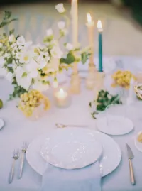Elegant reception place setting with white china, gold flatware, and soft floral accents, styled for a Santa Barbara wedding editorial by Yuliya Supin Design